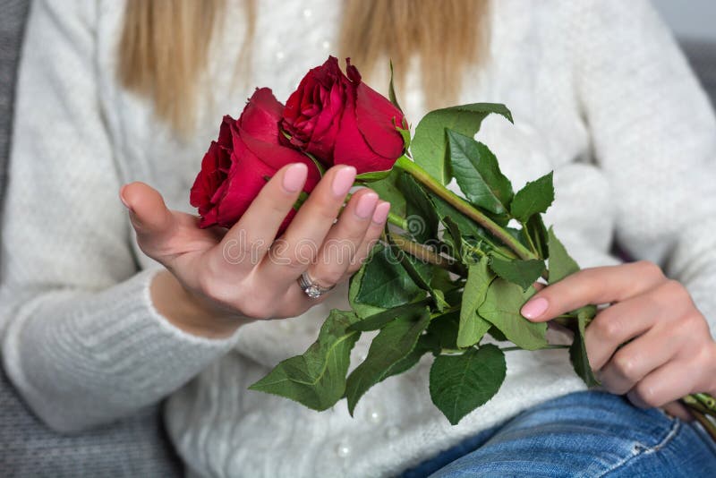Die junge Frau, die schönes Rot hält, stieg, in Hände und im Bett zu Hause in sitzen lizenzfreies stockbild Die junge Frau, die schönes Rot hält, stieg, in Hände und im Bett zu Hause in sitzen lizenzfreies stockbild