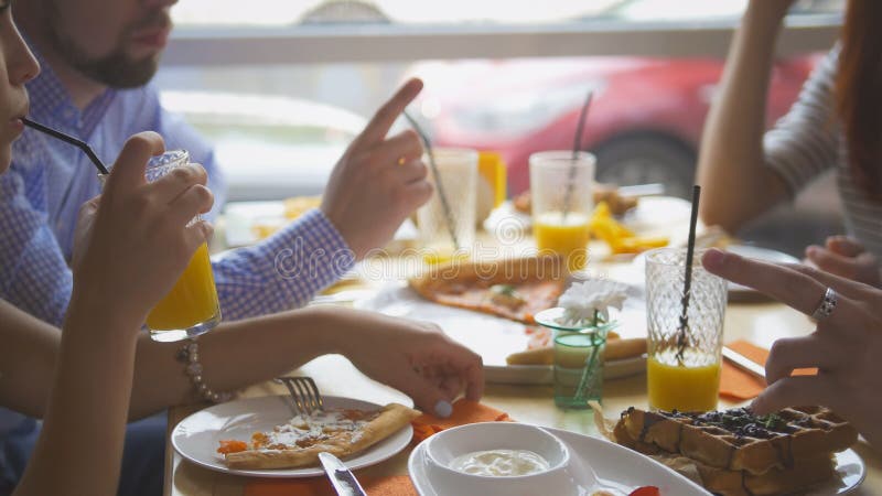 Die jungen Freunde, die Pizza nehmen, schneidet von der Platte auf Tabelle im Restaurant lizenzfreie stockfotografie Die jungen Freunde, die Pizza nehmen, schneidet von der Platte auf Tabelle im Restaurant lizenzfreie stockfotografie