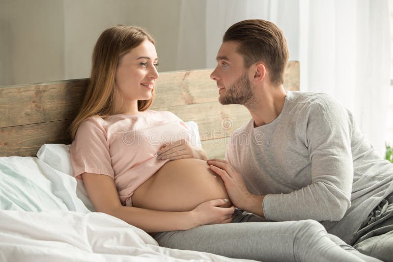 Die jungen Paare, die Baby erwarten, entspannen sich auf Bett zuhause lizenzfreies stockfoto Die jungen Paare, die Baby erwarten, entspannen sich auf Bett zuhause lizenzfreies stockfoto