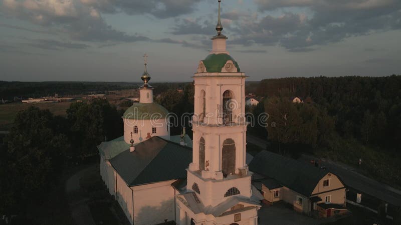 Die Kamera fliegt mit einem Glockenturm über die abendliche orthodoxe Kirche. das Dorf rakhmanovo moscow Region Luftaufnahmen.