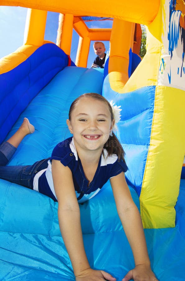 Die Kinder, die auf einem aufblasbaren Plättchen spielen, prallen Haus auf lizenzfreies stockbild Die Kinder, die auf einem aufblasbaren Plättchen spielen, prallen Haus auf lizenzfreies stockbild