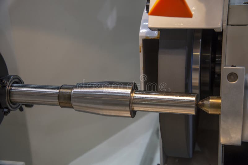 The metal shaft on the cylindrical grinding machine.The automotive part manufacturing process. The metal shaft on the cylindrical grinding machine.The automotive part manufacturing process