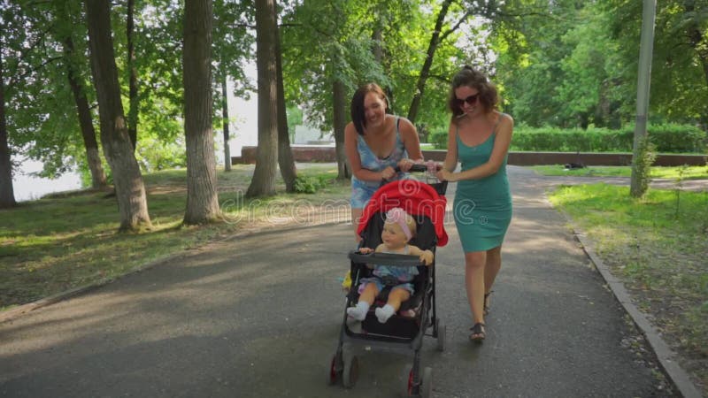 Die Mutter und ihr Freund gehen mit einem kleinen Kind, das in einem Spaziergänger sitzt