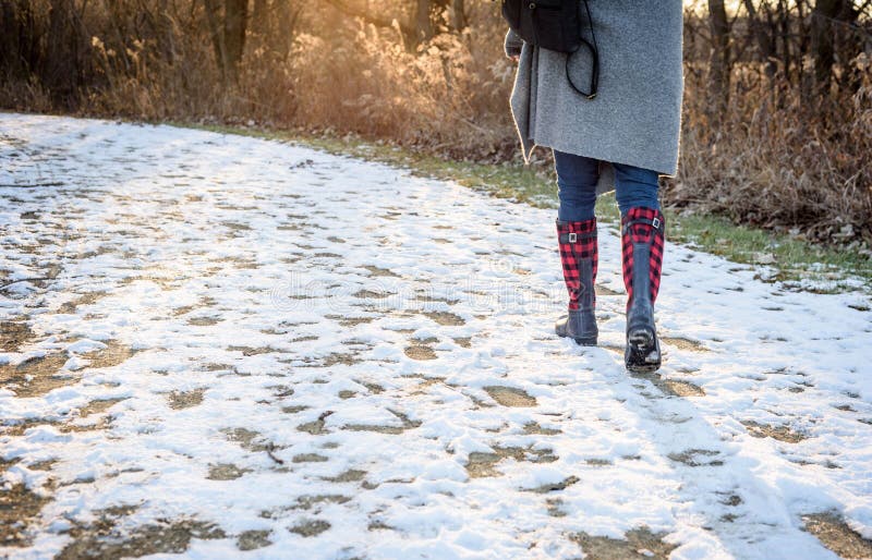Die niedrige Winkelsicht der Frau gehend auf Schnee bedeckte Spur in Holz a stockfoto Die niedrige Winkelsicht der Frau gehend auf Schnee bedeckte Spur in Holz a stockfoto
