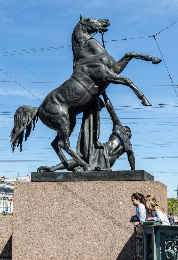 Die Pferdezahmere Statue auf Anichkov-Brücke und zwei jungen Mädchen am Fuß der Statue lizenzfreies stockbild Die Pferdezahmere Statue auf Anichkov-Brücke und zwei jungen Mädchen am Fuß der Statue lizenzfreies stockbild