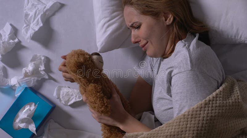 Die schreiende Frau, die Teddybären umarmt, brauchte Servietten auf Bett, Einsamkeit nach Bruch auf