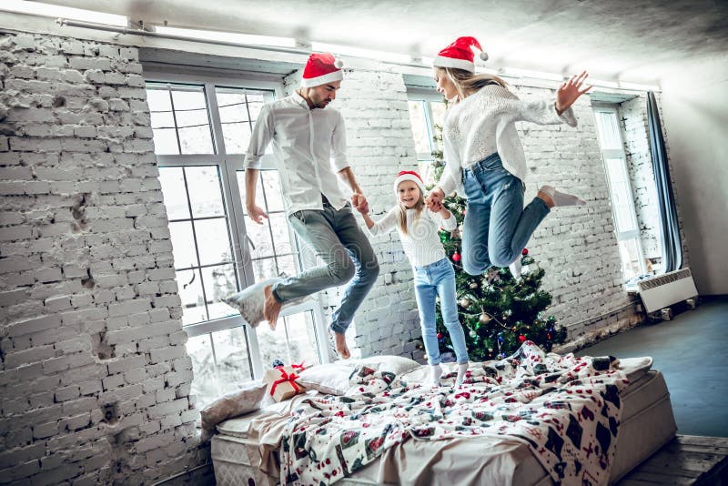 Die schöne Familie, die auf das Bett springt lizenzfreie stockbilder Die schöne Familie, die auf das Bett springt lizenzfreie stockbilder