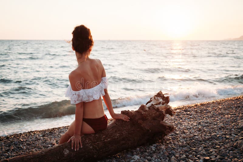 Die schöne junge Frau, die auf Strand bei Sonnenuntergang sitzt und meditiert lizenzfreie stockbilder Die schöne junge Frau, die auf Strand bei Sonnenuntergang sitzt und meditiert lizenzfreie stockbilder