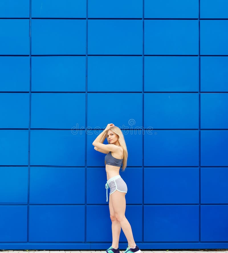 Die schöne Sportlerin wirft auf einem blauen Hintergrund auf stockbilder Die schöne Sportlerin wirft auf einem blauen Hintergrund auf stockbilder