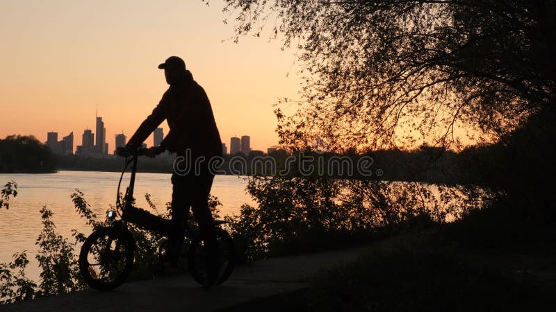 Die Silhouette eines Radfahrers vor dem Hintergrund des abendlichen Warschauer. eine große Stadt bei Sonnenuntergang.