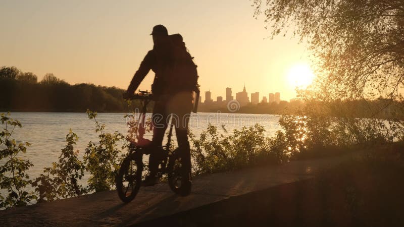 Die Silhouette eines Radfahrers vor dem Hintergrund des abendlichen Warschauer. eine große Stadt bei Sonnenuntergang.