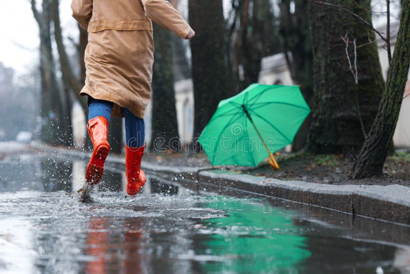 Die vrouw in rubberlaarzen dagclose-up na paraplu op regenachtige lopen