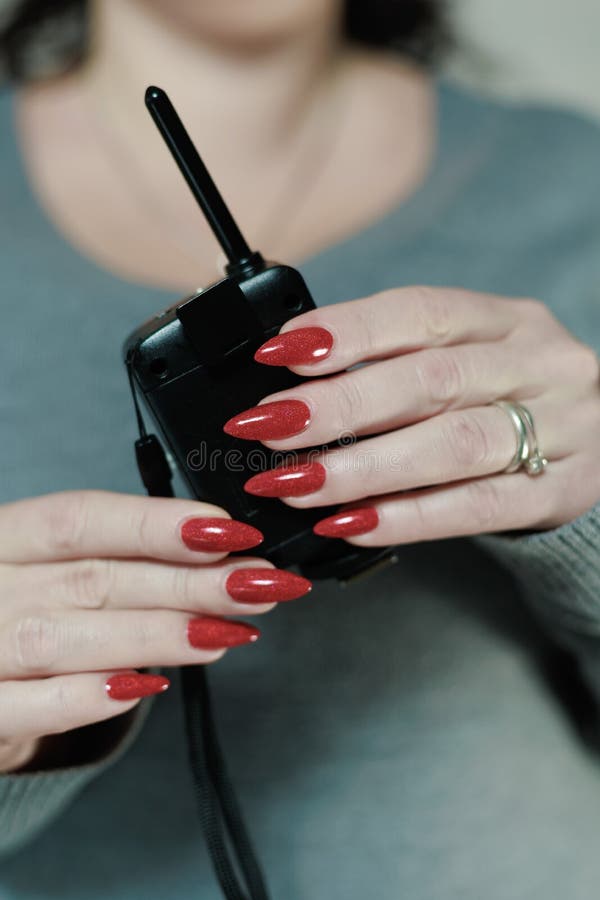 Die weibliche Hand mit langen Nägeln und einer dunkelroten Maniküre hält eine Flasche Nagellack stockbilder