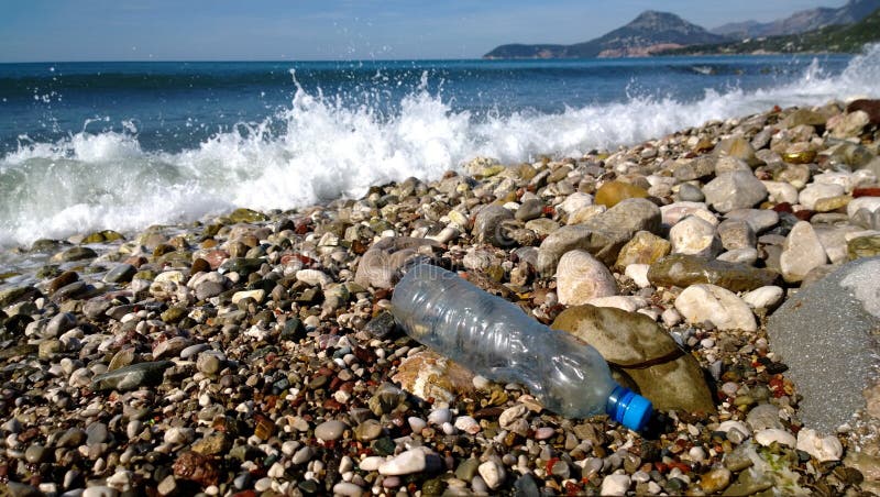 Die Wellen des Meeres wuschen sich herauf eine leere Plastikflasche Umweltverschmutzung - Abfall in den szenischen Stellen