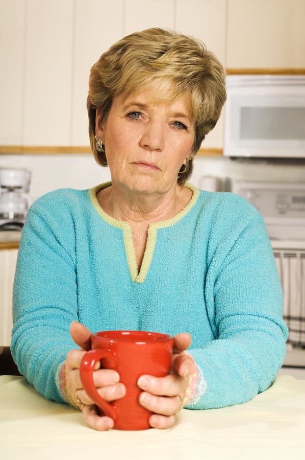 Senior woman holds a coffee mug, looking unhappy. Senior woman holds a coffee mug, looking unhappy.