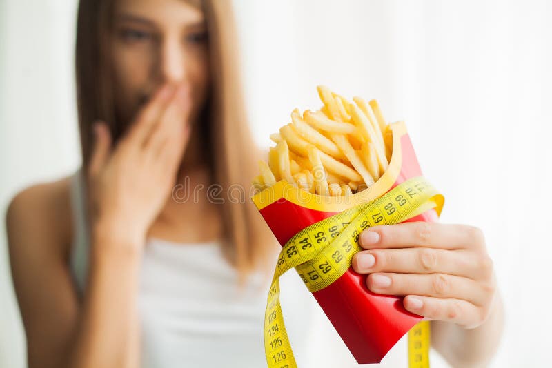Dieet Vrouw die zich op schalen bevinden en chips houden Het concept het gezonde eten Gezonde Levensstijl Dieet stock afbeelding Dieet Vrouw die zich op schalen bevinden en chips houden Het concept het gezonde eten Gezonde Levensstijl Dieet stock afbeelding