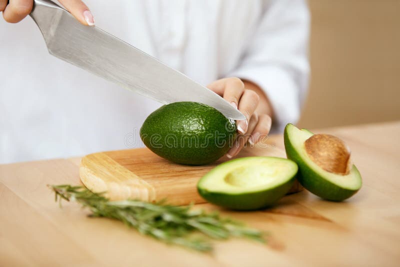 Dieet Vrouwelijke Handen die Avocado in Keuken snijden