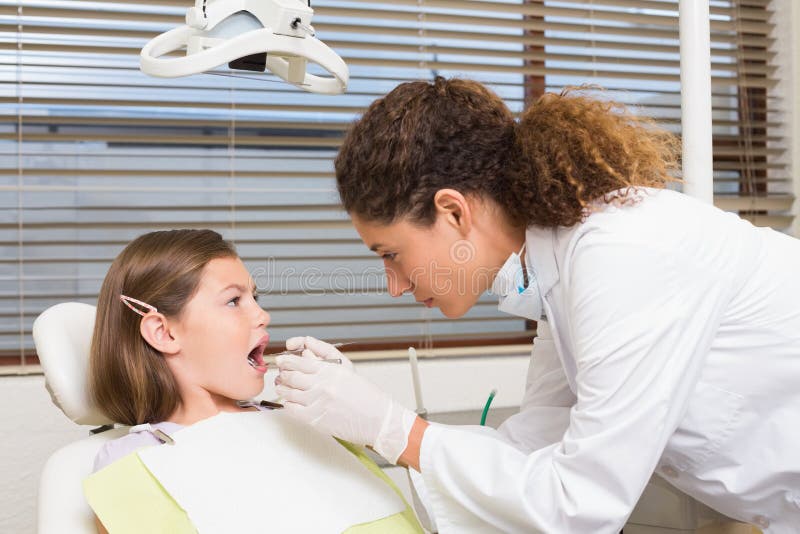 Pediatric dentist examining little girls teeth in the dentists chair at the dental clinic. Pediatric dentist examining little girls teeth in the dentists chair at the dental clinic