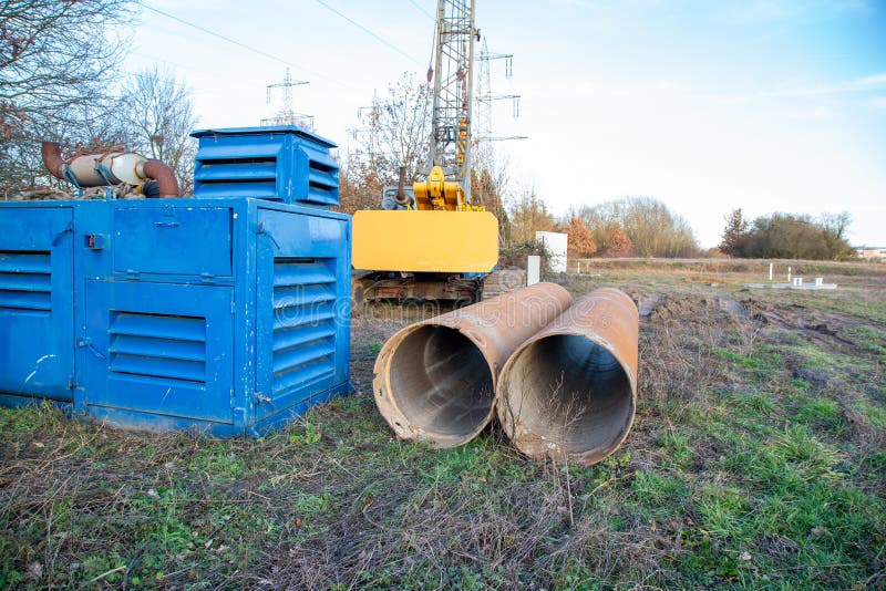 Diesel aggregate and large drill pipes with yellow jib crane for well drilling royalty free stock images