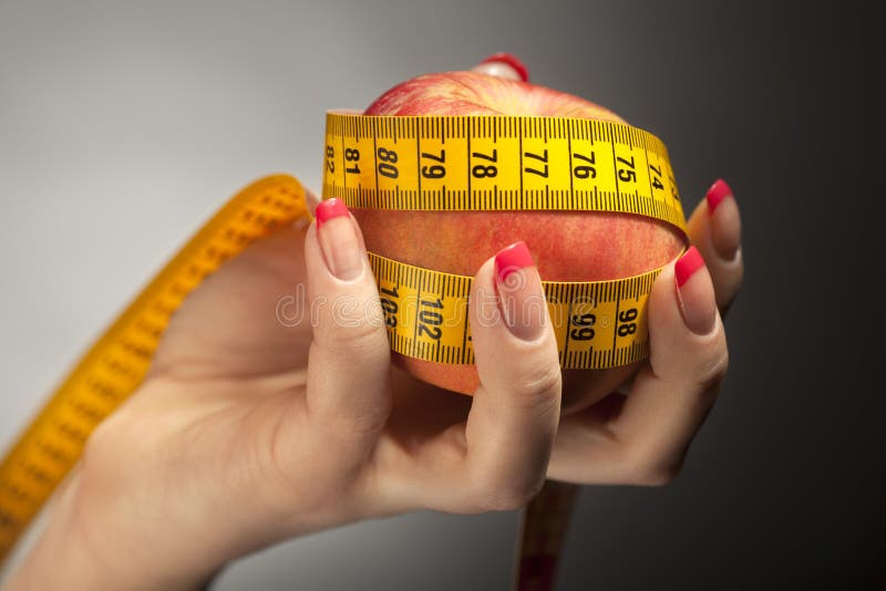 Diet apple with measure tape in woman hand stock image Diet apple with measure tape in woman hand stock image