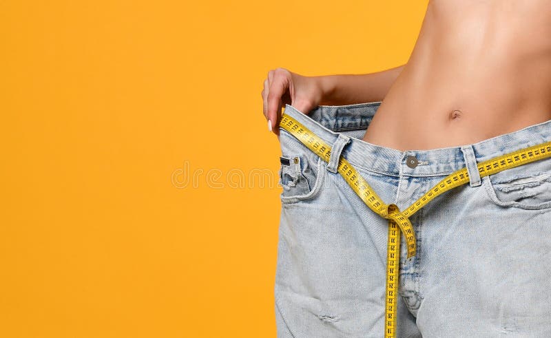 Thin woman in jeans measures waist, weight loss Stock Photo by