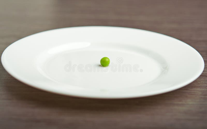 Diet concept. one pea on an empty white plate