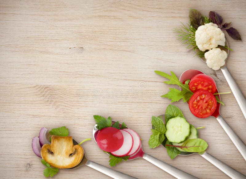 Diet concept of spoons with sliced vegetables on wooden board