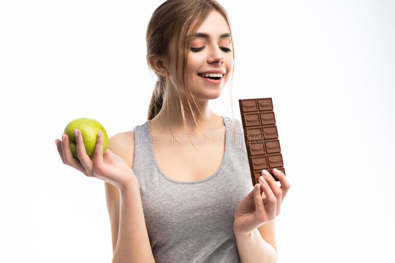 Diet. Dieting concept. Healthy Food. Beautiful Young Woman choosing between Healthy and Unhealthy Food.Fruits or Sweets royalty free stock photo Diet. Dieting concept. Healthy Food. Beautiful Young Woman choosing between Healthy and Unhealthy Food.Fruits or Sweets royalty free stock photo
