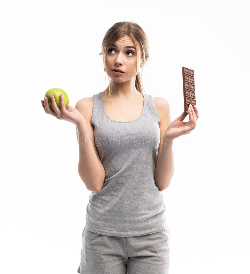 Diet. Dieting concept. Healthy Food. Beautiful Young Woman choosing between Healthy and Unhealthy Food.Fruits or Sweets stock photos Diet. Dieting concept. Healthy Food. Beautiful Young Woman choosing between Healthy and Unhealthy Food.Fruits or Sweets stock photos