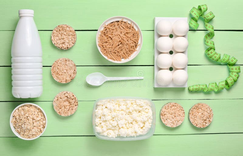 Diet, healthy food. Bottle of yogurt, crispy round bread, buckwheat noodles, oatmeal, cottage cheese, egg tray on a blue wooden b