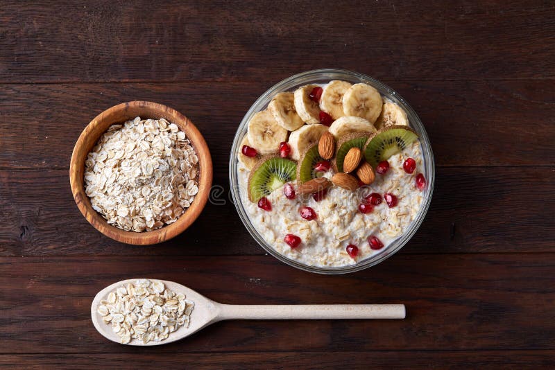 Diety śniadaniowy oatmeal z owoc, pucharem i łyżką z owsów płatkami, selekcyjna ostrość, zakończenie zdjęcie stock Diety śniadaniowy oatmeal z owoc, pucharem i łyżką z owsów płatkami, selekcyjna ostrość, zakończenie zdjęcie stock
