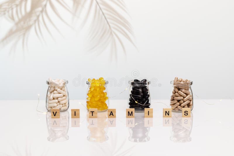 A set of vitamin and supplement capsules in transparent jars, palm leaves on a white table with reflection. Natural herbs, organic pills, vitamins from medicinal plants. Biologically active additives. A set of vitamin and supplement capsules in transparent jars, palm leaves on a white table with reflection. Natural herbs, organic pills, vitamins from medicinal plants. Biologically active additives