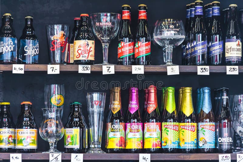Different brands of Belgian beer bottles and glasses in a liquor