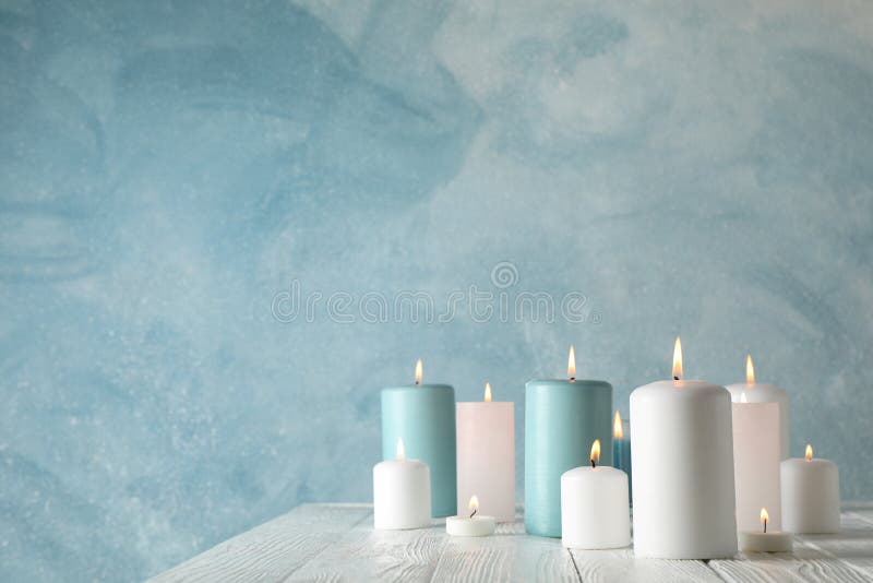Different burning candles against blue background stock images