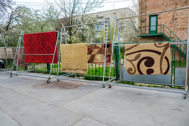Different Carpets Hanging on Rack Outdoors. Professional Carpet