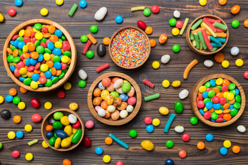 different colored round candy in bowl and jars. Top view of large variety sweets and candies with copy space