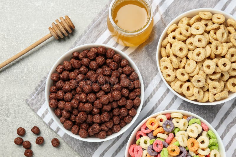 Different Delicious Breakfast Cereals and Honey on Light Grey Table