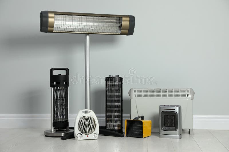 Different Electric Heaters Near Light Grey Wall Indoors Stock Image