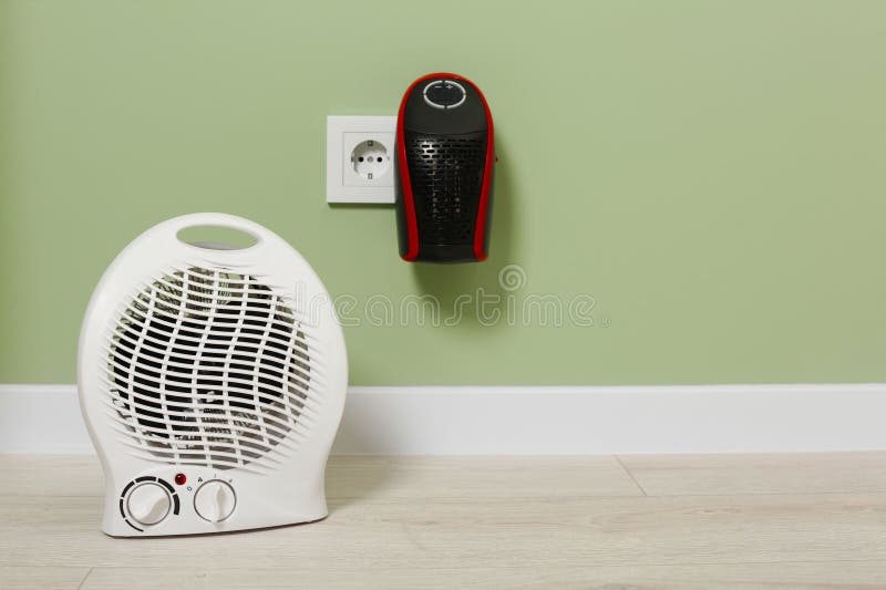 Different Electric Heaters Near Pale Green Wall Indoors. Space for Text