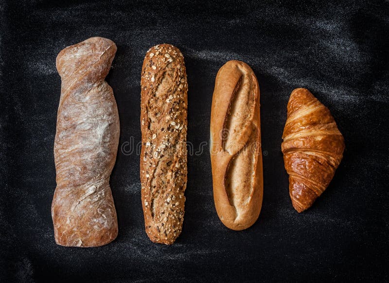 Different kinds of bread rolls on black chalkboard from above. Kitchen or bakery poster design. Different kinds of bread rolls on black chalkboard from above. Kitchen or bakery poster design.