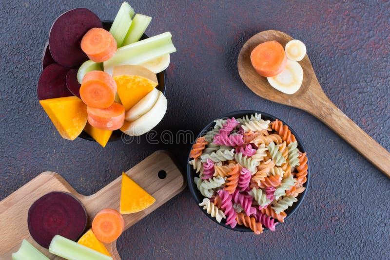 Different kinds of colorful raw italian pasta and its natural vegetable dyes celery, beet, carrot, pumpkin, parsnip.