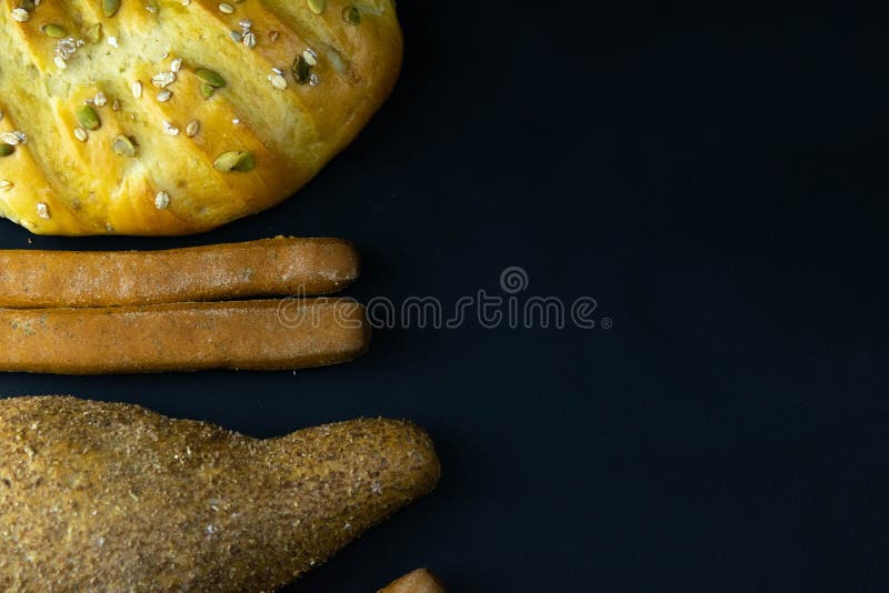Different kinds of fresh bread with grain on black rustic background. bread stand left stock images