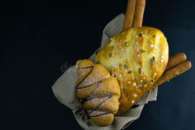 Different kinds of fresh bread with grain on black rustic background stock image