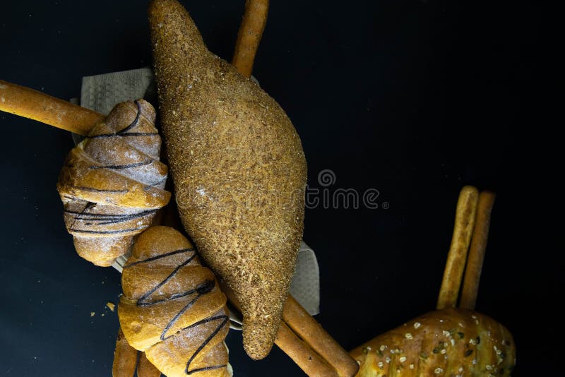 Different kinds of fresh bread with grain on black rustic background royalty free stock image