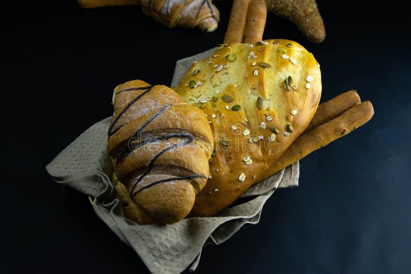 Different kinds of fresh bread with grain on black rustic background royalty free stock image