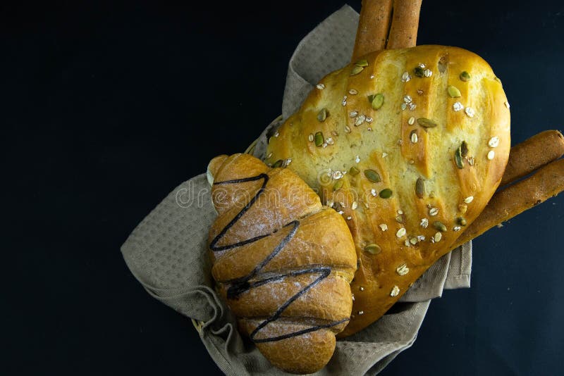 Different kinds of fresh bread with grain on black rustic background stock photography