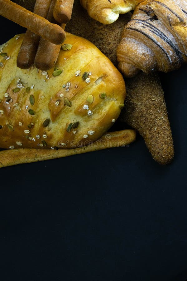 Different kinds of fresh bread with grain on black rustic background stock images