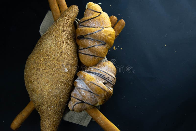 Different kinds of fresh bread with grain on black rustic background stock images