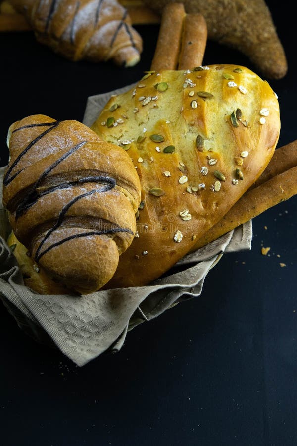 Different kinds of fresh bread with grain on black rustic background royalty free stock photos
