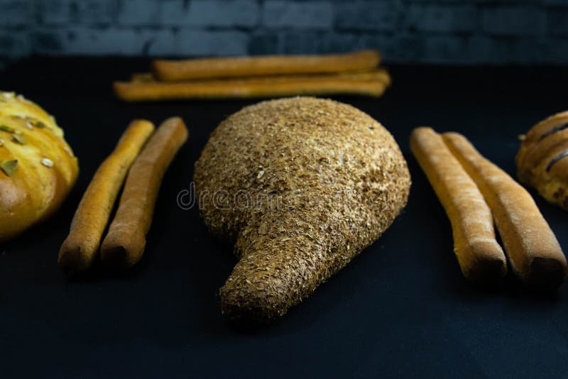 Different kinds of fresh bread with grain on black rustic background royalty free stock images